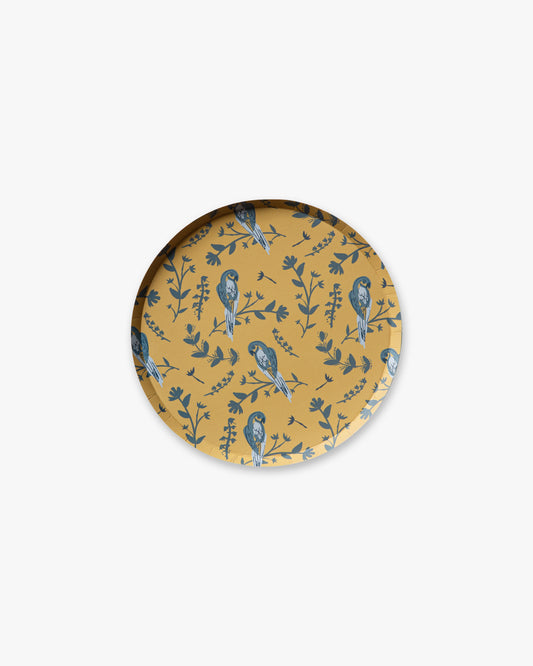 Round plate with bird and leaf pattern on a mustard yellow background