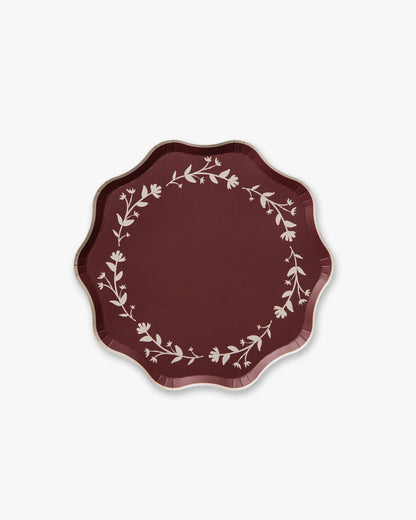 Decorative deep red plate with floral pattern on a white background
