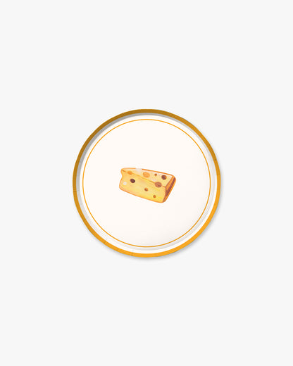 Small wedge of cheese on a decorative plate with a gold rim against a white background