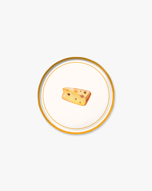 Small wedge of cheese on a decorative plate with a gold rim against a white background