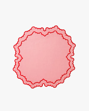 Pink scalloped circle placemat on a white background