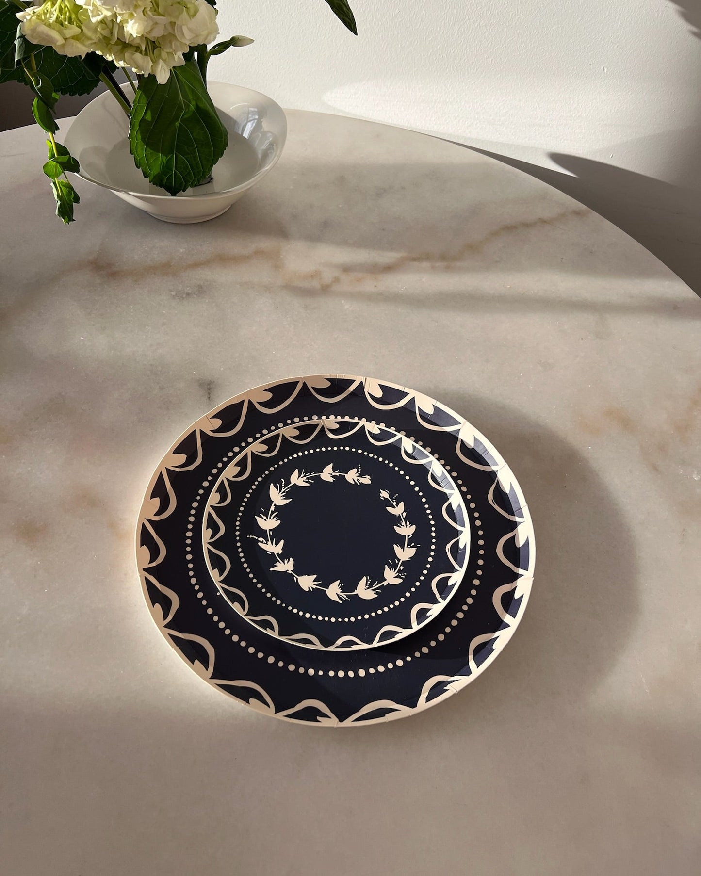 Navy blue plate with white floral pattern on a marble table.