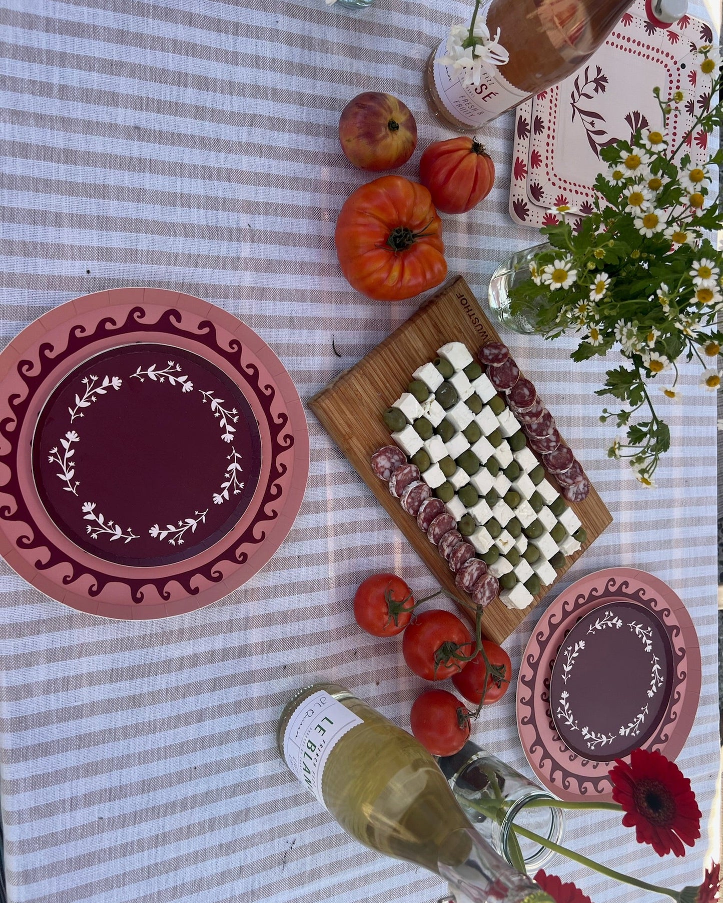 Table setting with plates, food, and flowers on a checkered tablecloth