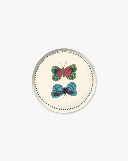 A round decorative plate cream background, featuring two illustrated butterflies—one green and red, the other blue and black—centered within a dotted green border.