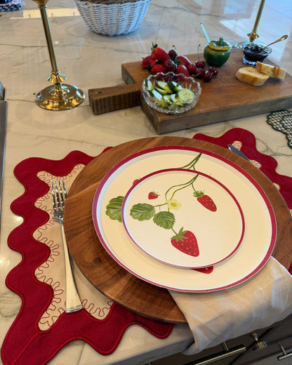 A place setting with stacked plates that have a strawberry design