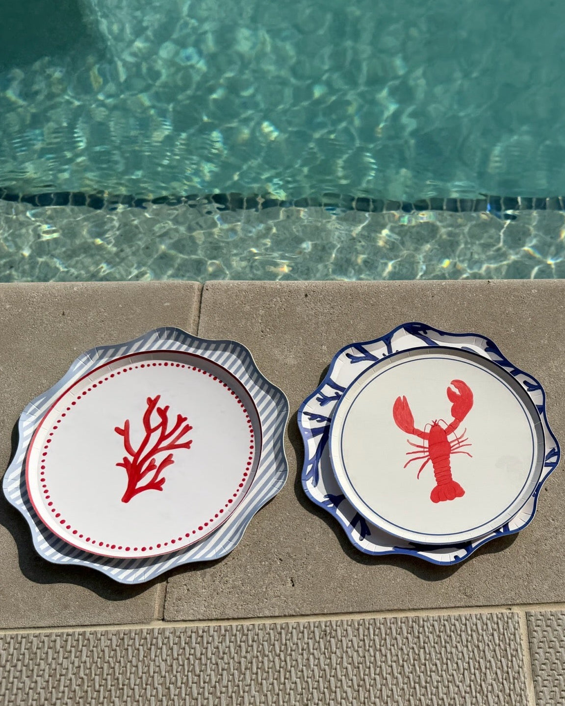 Decorative plats with a lobster and a coral sitting next to a pool