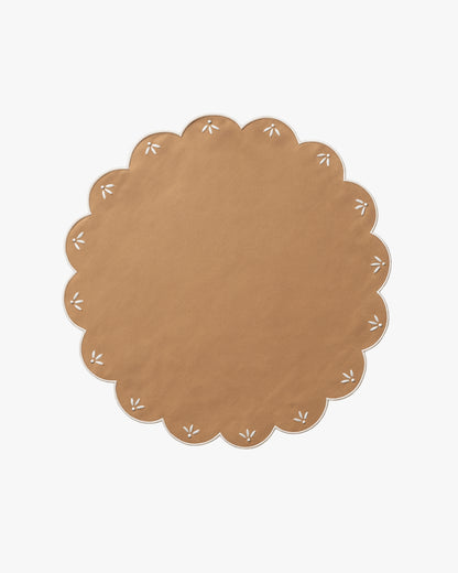 Round brown placemat with white floral patterns on a white background