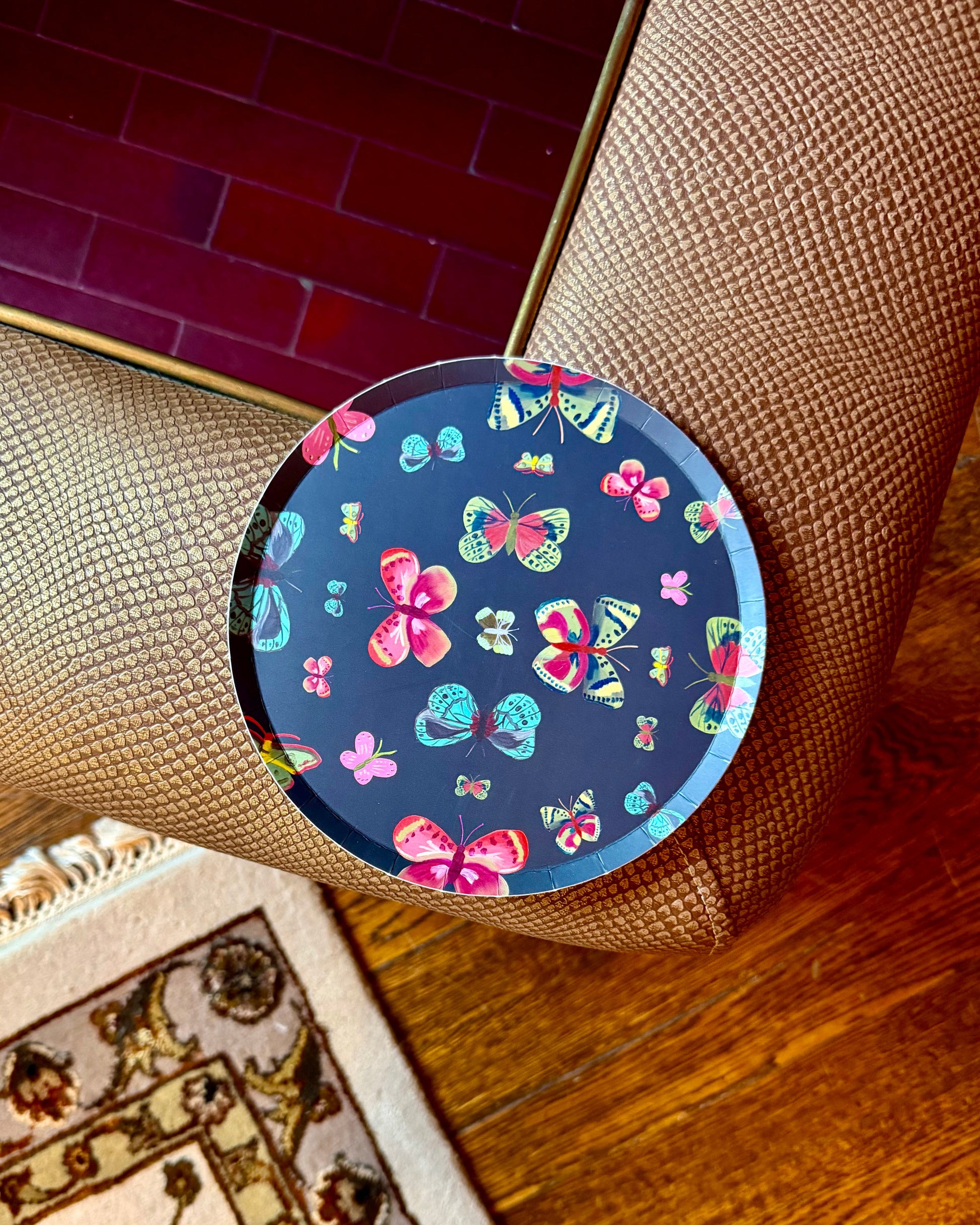 A round decorative plate with a colorful butterfly pattern on a dark blue background.
