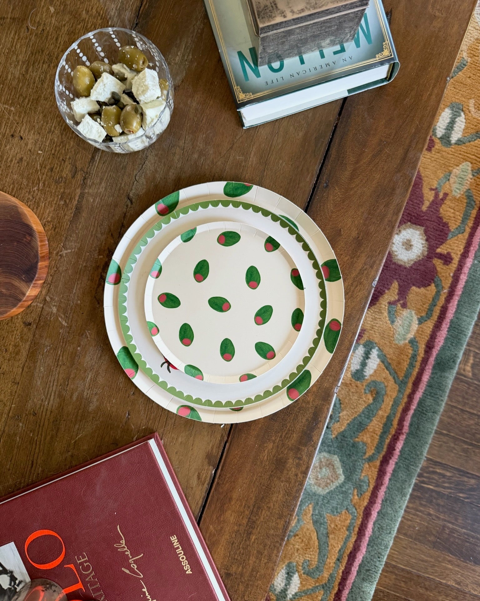 Plates with olives on a wooden table with snacks and books