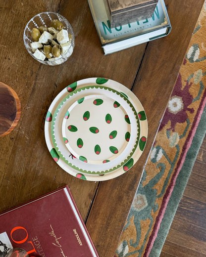 Plates with olives on a wooden table with snacks and books