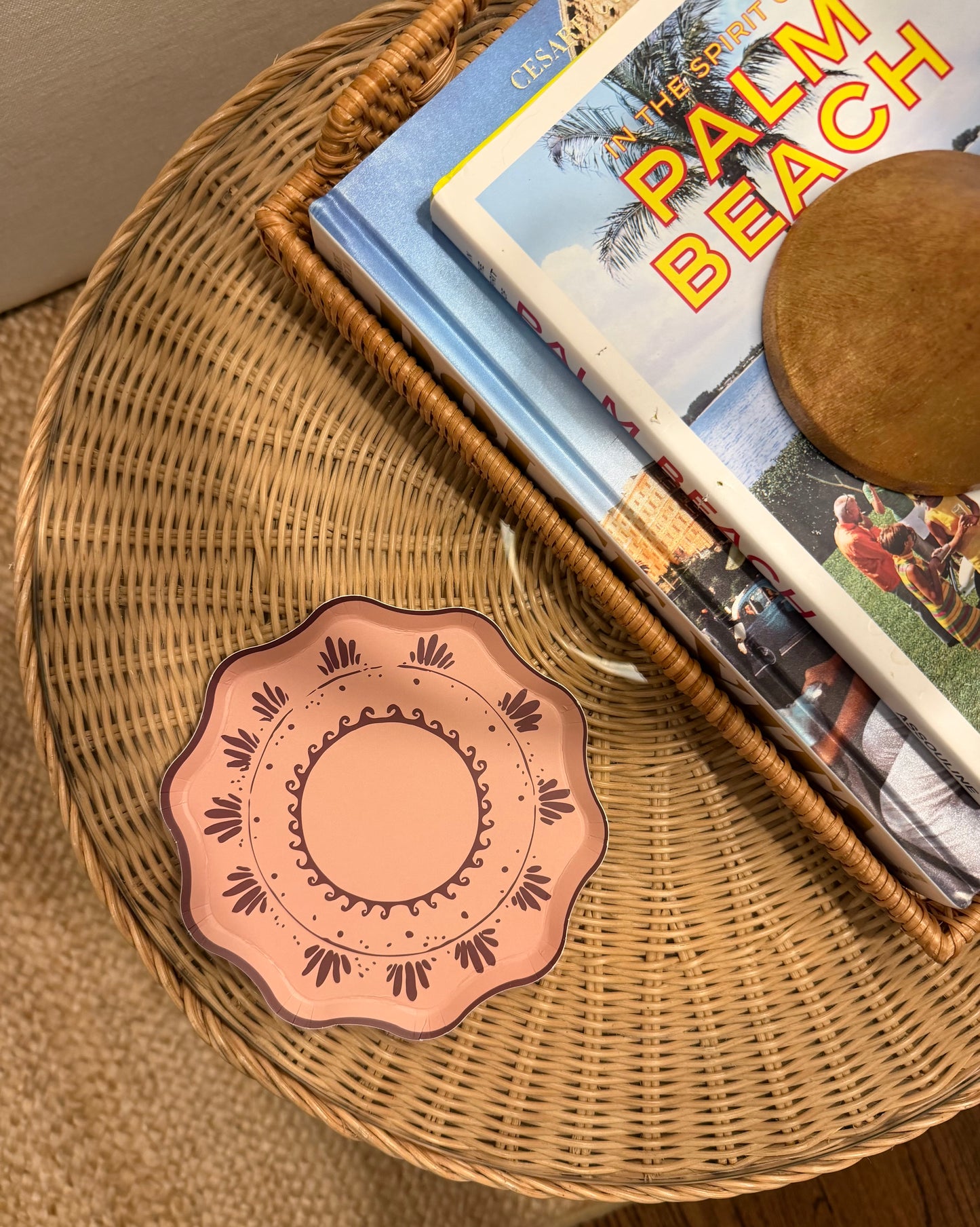Decorative plate on a wicker table with a book titled 'Palm Beach'.