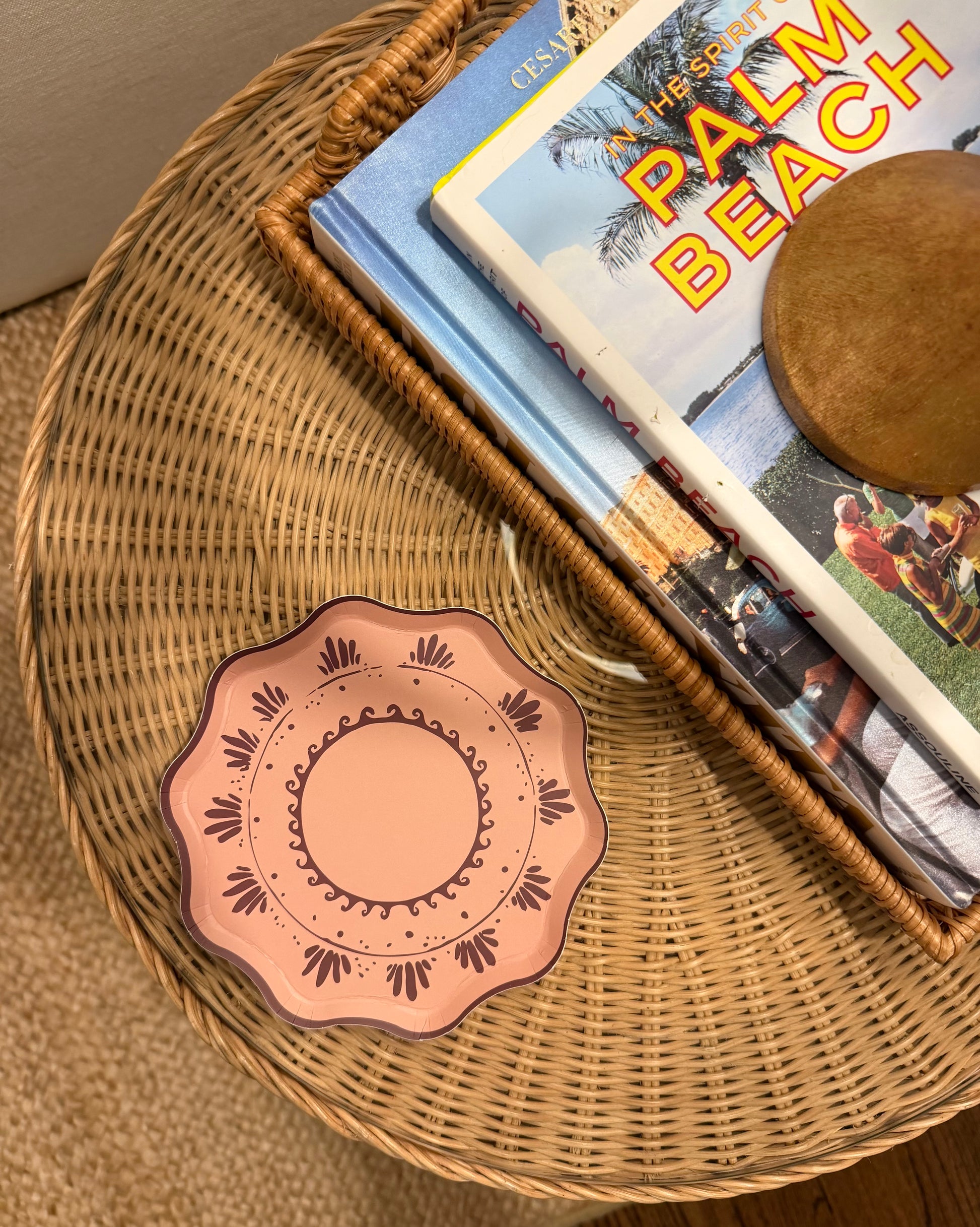 Decorative plate on a wicker table with a book titled 'Palm Beach'.
