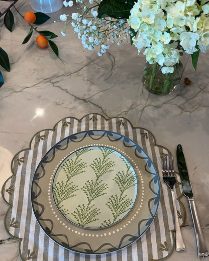 Decorative plates layered on a striped placemat and florals in the background