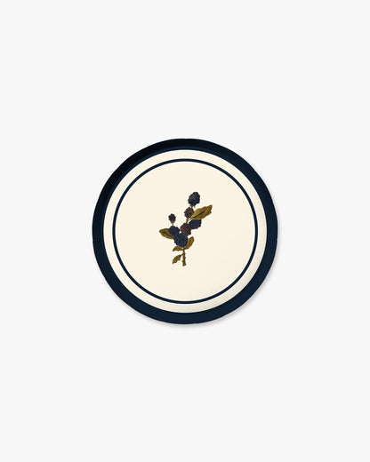 A round decorative plate with a cream center, a navy blue outer ring, and a small central blackberry motif.