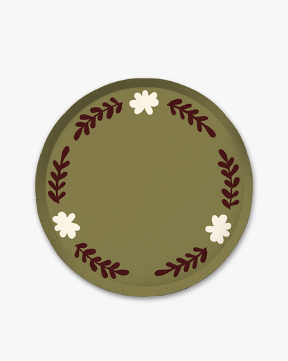 A round olive green paper plate featuring a decorative wreath design with dark red leafy stems and three small white flowers, shown on a light gray background.