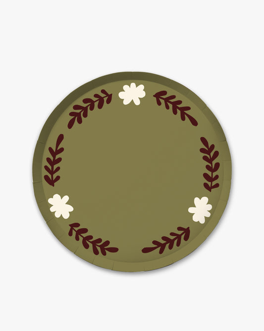 A round olive green paper plate featuring a decorative wreath design with dark red leafy stems and three small white flowers, shown on a light gray background.