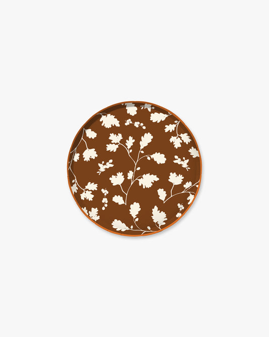 Dark brown paper plate with white silhouette pattern of fall leaves. 