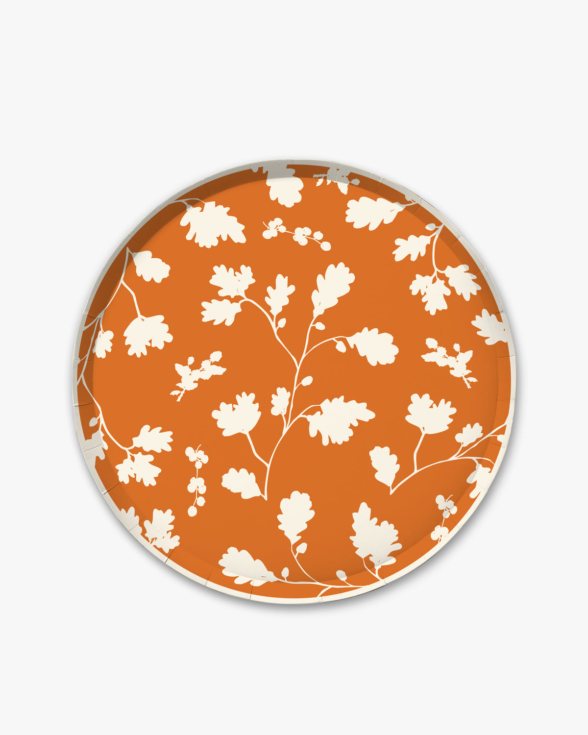 Orange paper plate with white silhouette pattern of fall leaves. 