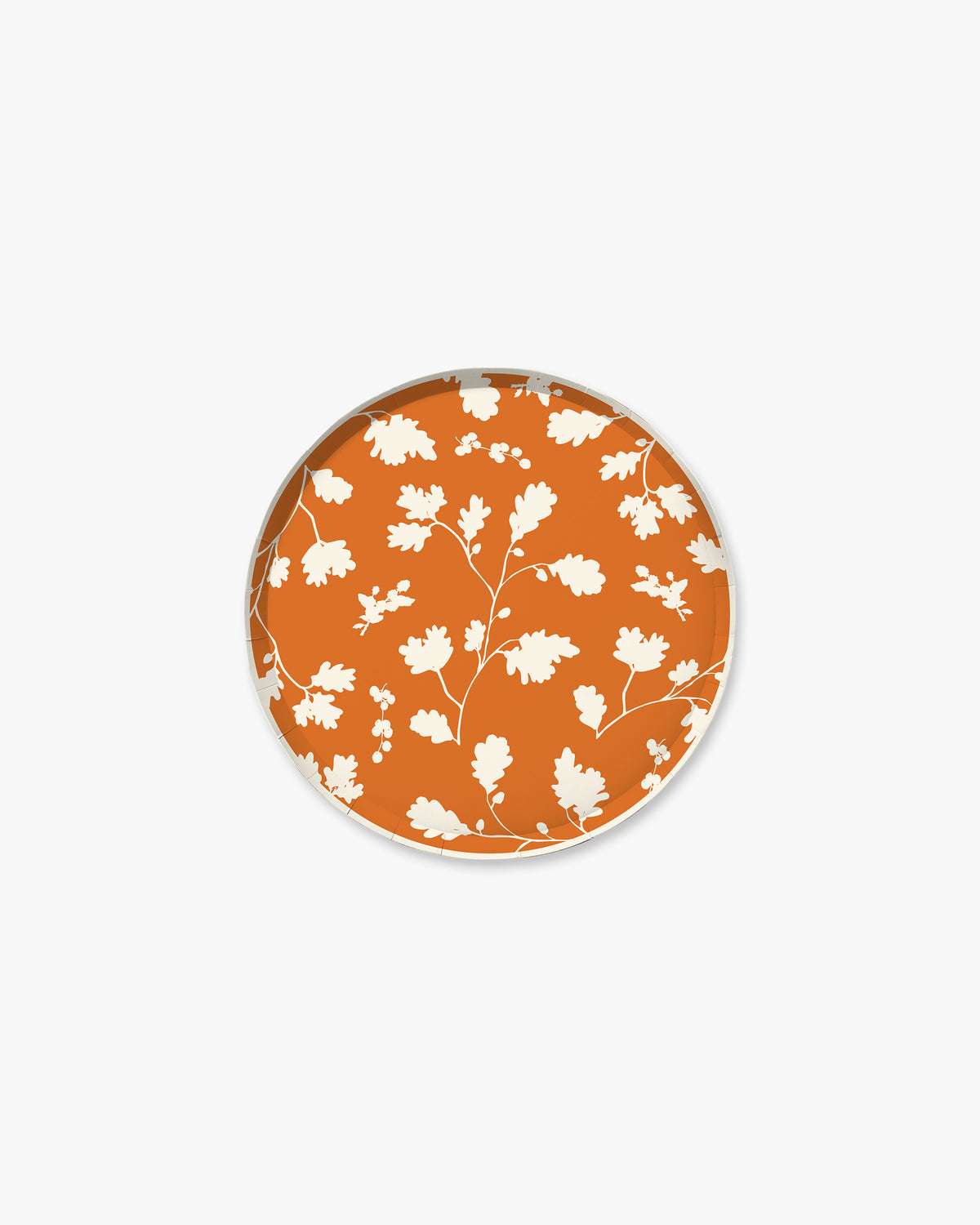 Orange paper plate with white silhouette pattern of fall leaves. 