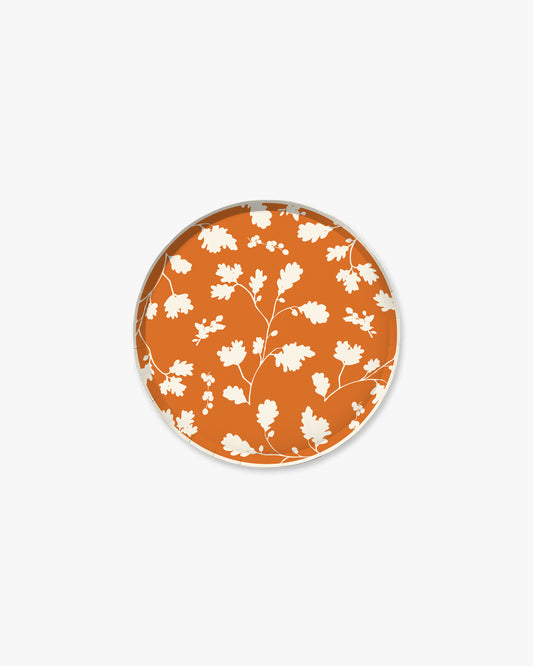 Orange paper plate with white silhouette pattern of fall leaves. 