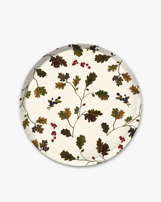 A round paper plate with a vintage botanical pattern of oak leaves and small berries on an off-white background, shown against a light gray studio backdrop.