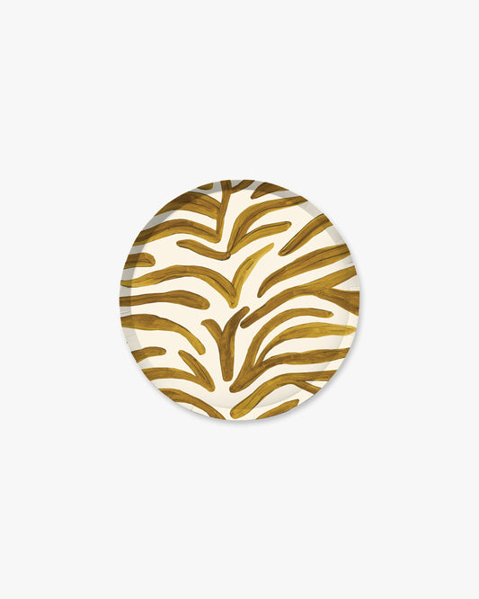 A round paper plate featuring a gold zebra-stripe pattern on a white background, centered on a light gray studio backdrop.