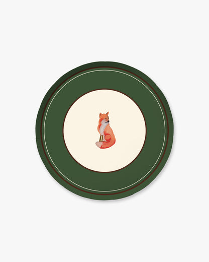 A round decorative plate featuring a dark green outer border with thin gold and brown concentric lines, a cream center, and a small illustrated fox sitting in the middle.