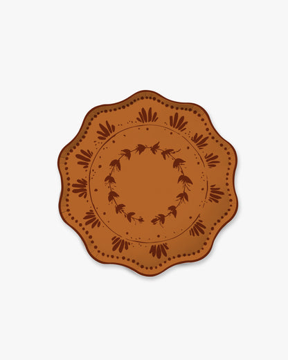 A round decorative plate with a scalloped edge, featuring a brown and terracotta orange floral pattern on a light gray background.