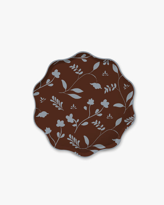 A scalloped oval plate featuring a dark brown background with a light gray floral and leaf pattern, shown against a plain light gray background.
