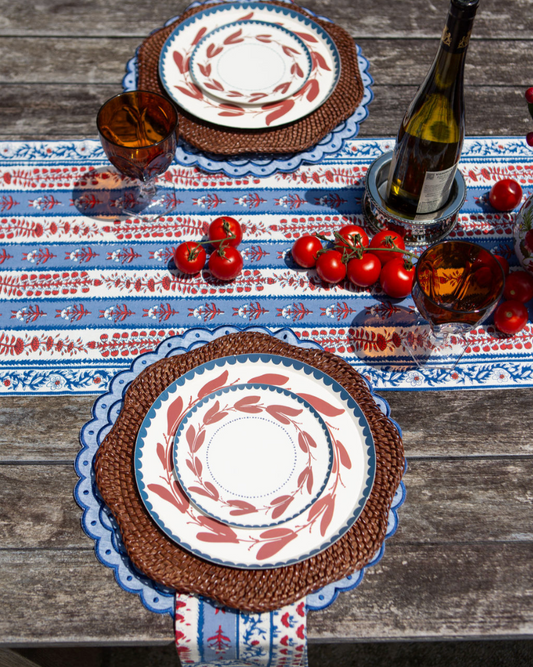 Table setting with red, white, and blue tablecloth, plates, and glasses on a wooden table.