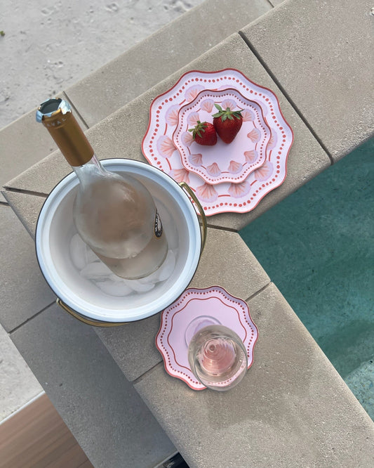 Decorative pink plates on the pool edge with a bucket of wine