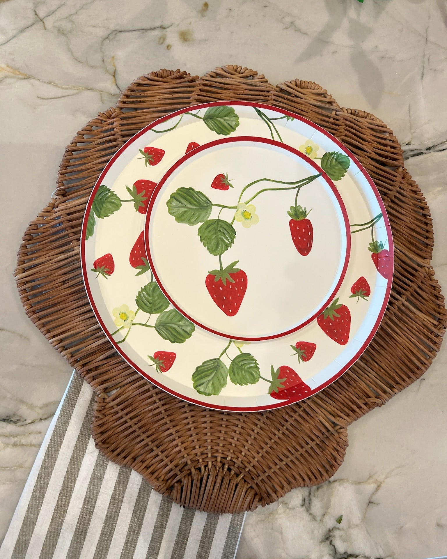Plates with strawberries on them on a marble counter. 