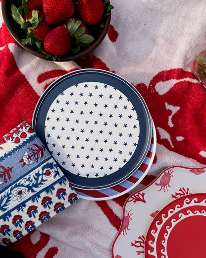 plates on a towel that are blue and red with a bowl of strawberries
