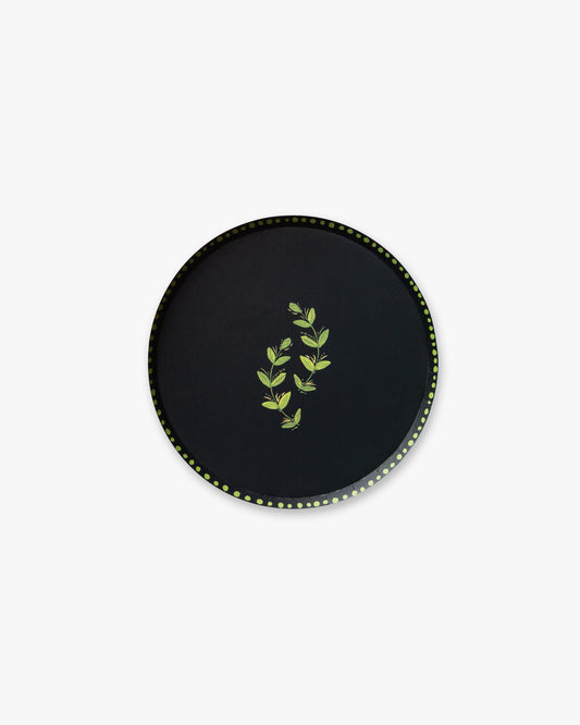 Round navy plate with green leaf design on a white background
