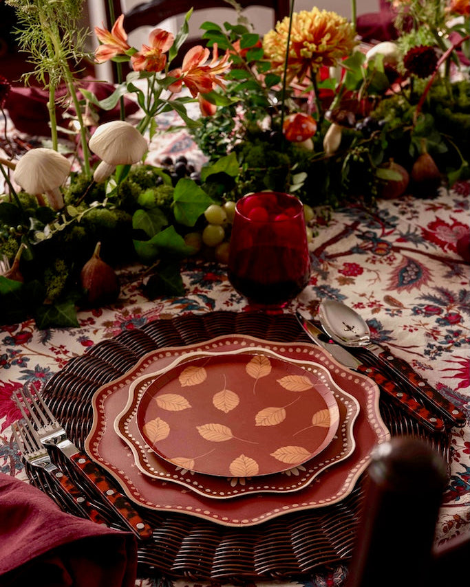 a tablescape with a floral centerpiece and deep red and gold plates