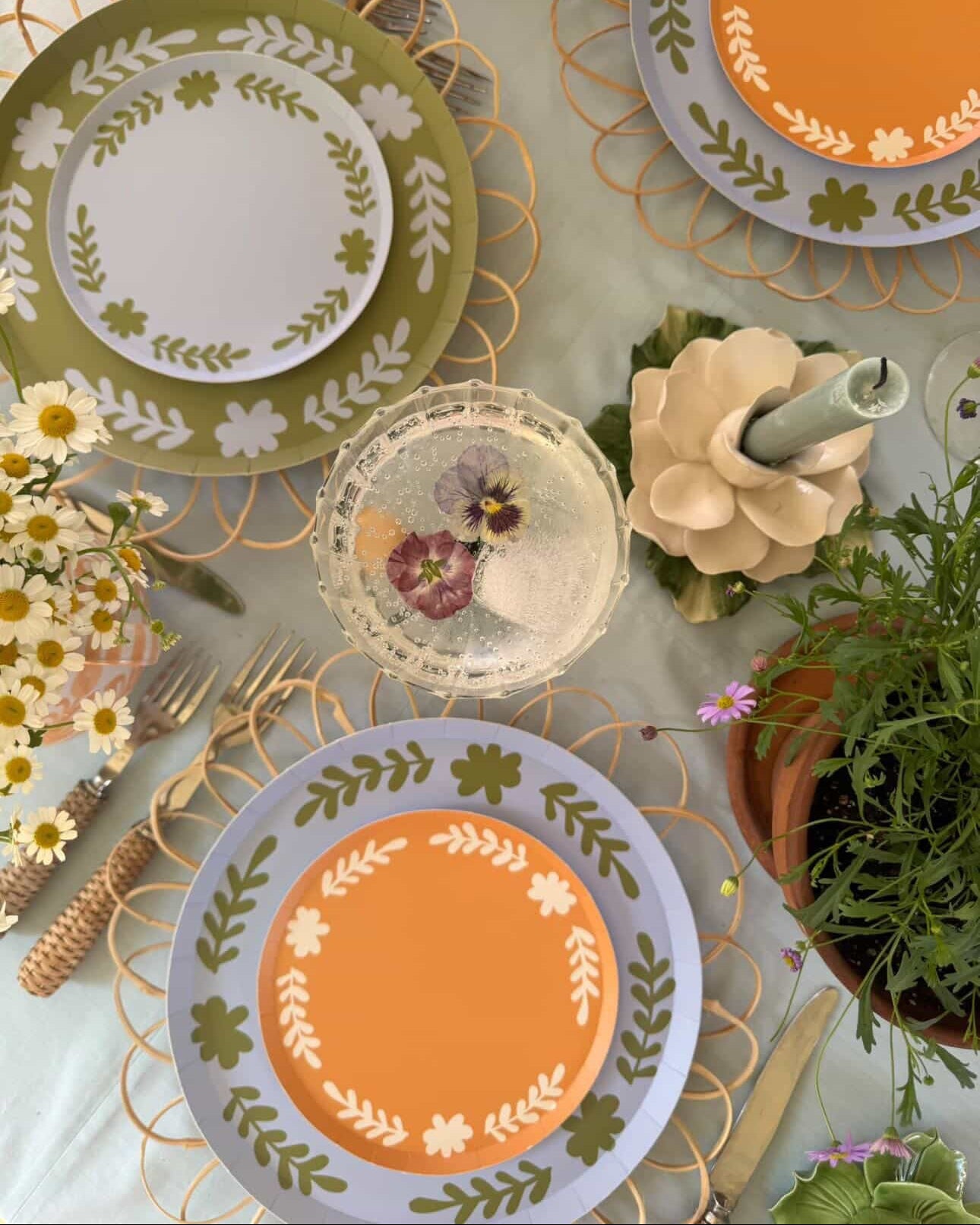 Decorative table setting with floral-patterned plates and cutlery on a light surface.