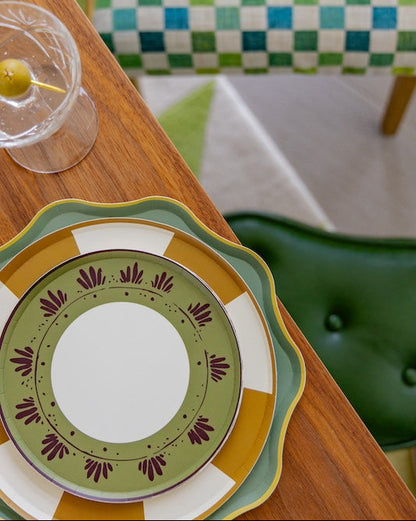 a stack of decorative plates on a wooden table with a martini glass