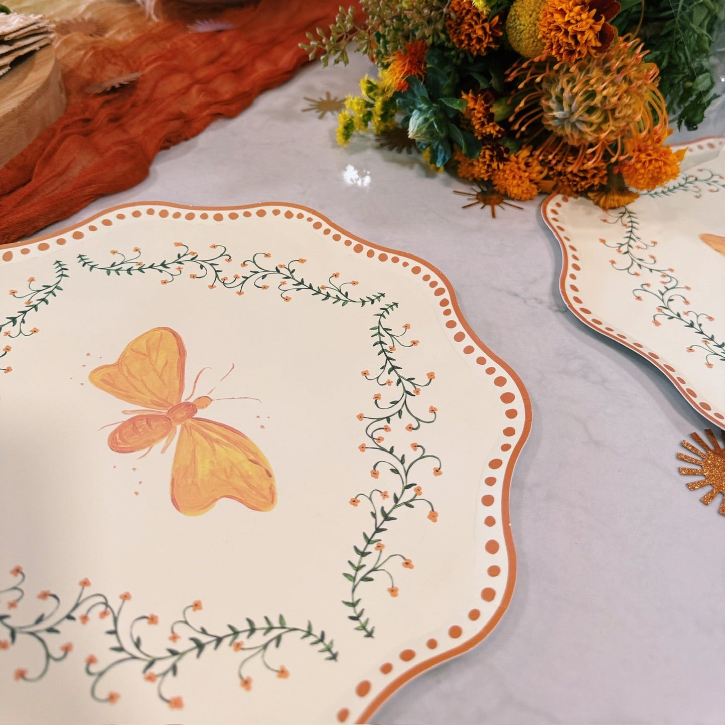 Decorative table setting with a butterfly design on the plate, flowers, and a bowl.