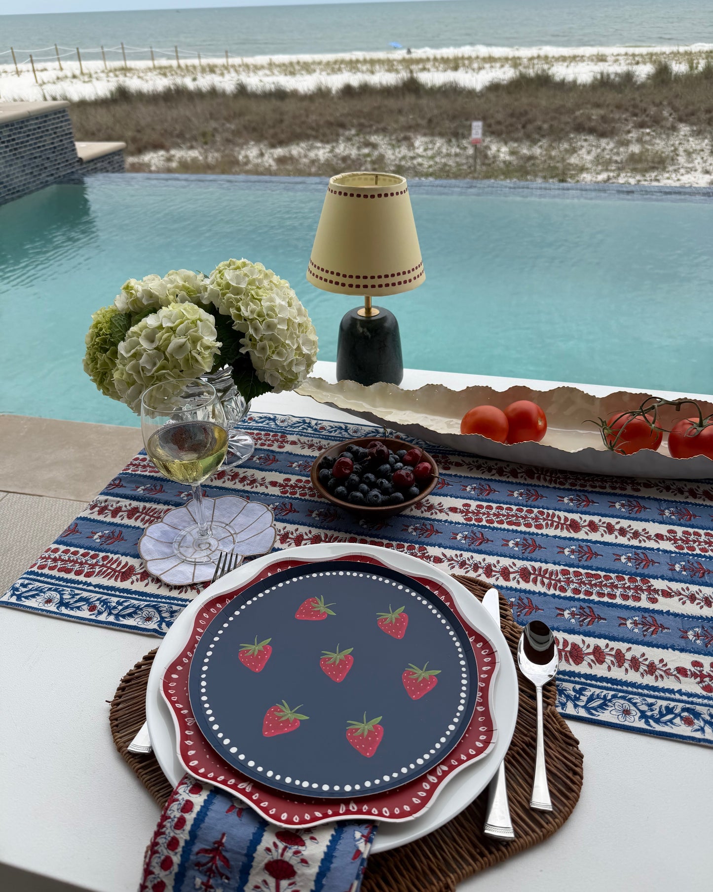 a table setting with decorative plates set by a pool