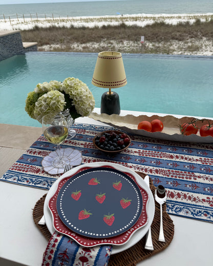 a table setting with decorative plates set by a pool
