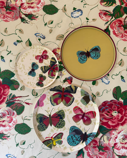 decorative plates with different butterfly patterns set on a floral table cloth.