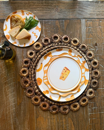 a dinner table with layered yellow plates with cheese on it.