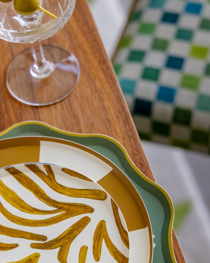 A close-up of a decorative plates set on a wooden table next to a wine glass.