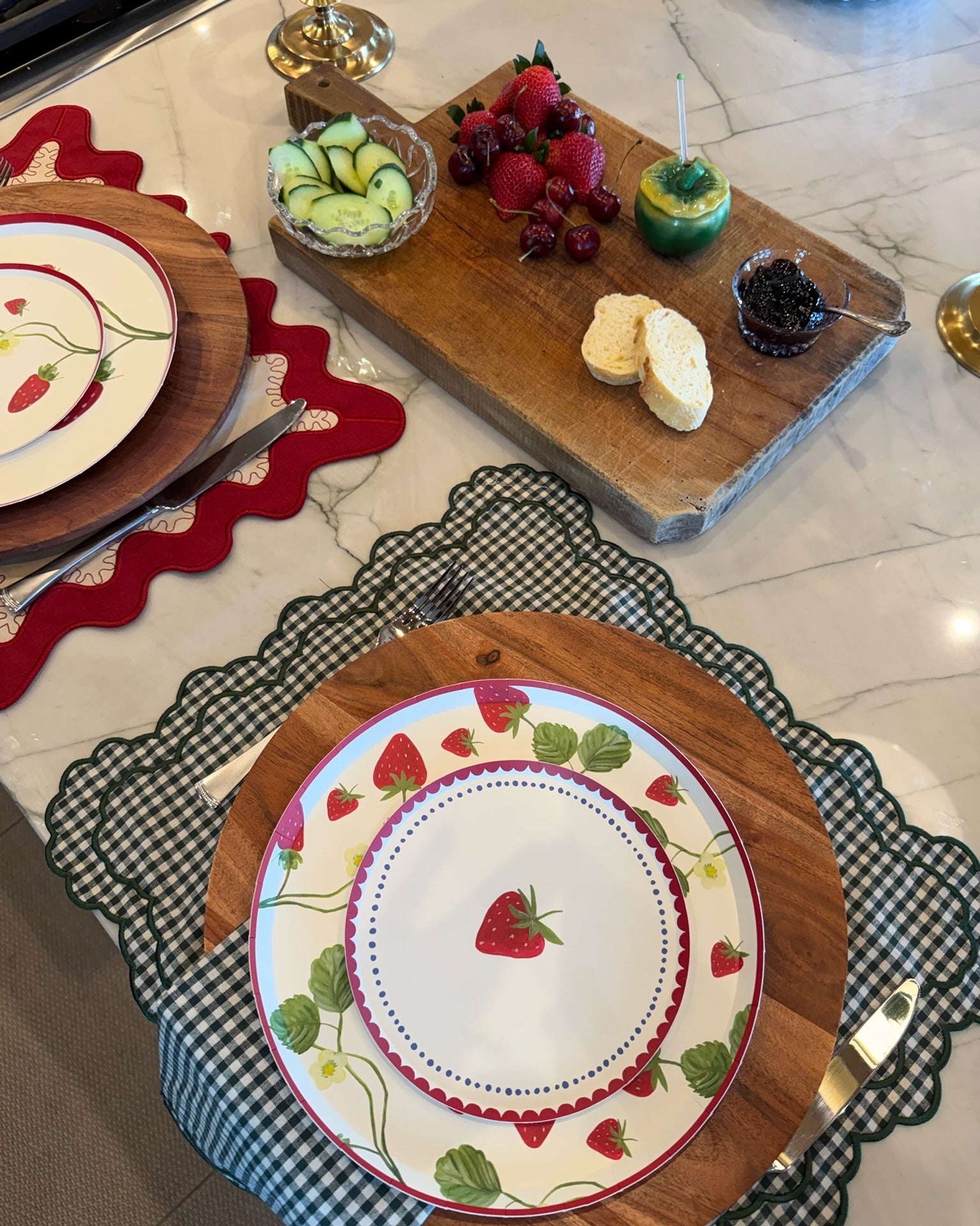 two place setting with plates that have strawberries on them. 